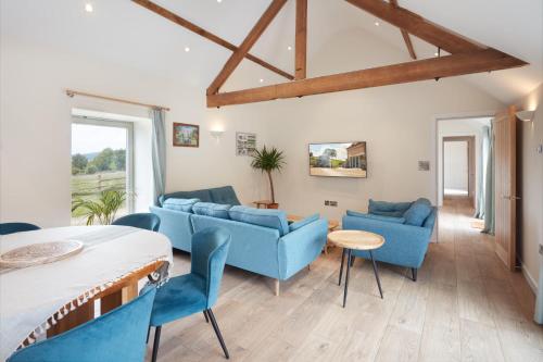 a living room with blue couches and a table at Hayes Farm - 8 Houses in Gloucester