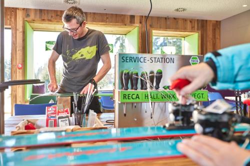 a man is standing behind a table with a machine at Explorer Hotel Hinterstoder in Hinterstoder