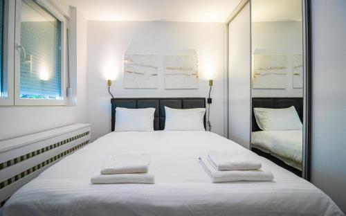 a bedroom with a large white bed with two mirrors at Sunny Nest Apartment in Fontana