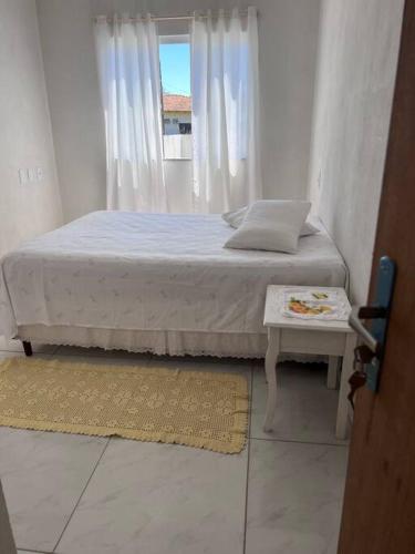 a white bedroom with a bed and a window at Casa praia em Penha - disponível in Penha