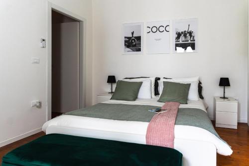 a bedroom with a large white bed with a green blanket at [Angolo45]Vista Inedita su Udine in Passons