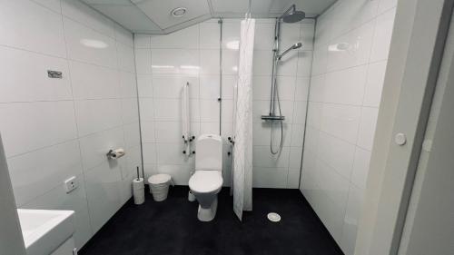 a white bathroom with a toilet and a sink at Rentalux Apartment Rooms in Timrå
