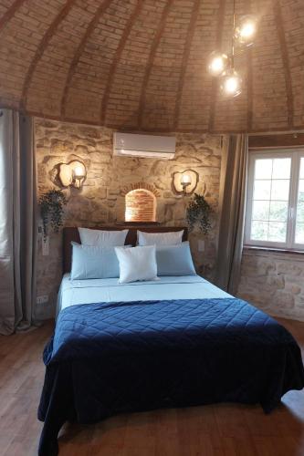 une chambre avec un grand lit dans un mur de pierre dans l'établissement Domaine de la Tour de Pérès, à Ayguetinte