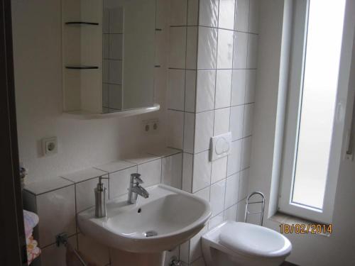 a white bathroom with a sink and a toilet at Haus Perkow 
