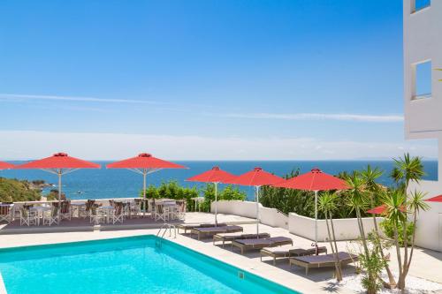 a swimming pool with umbrellas and chairs and the ocean at Doryssa Lithos Hotel in Pythagoreio