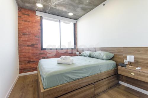 1 dormitorio con 1 cama con pared de ladrillo en Shopping Del Sol's Finnest, en Asunción