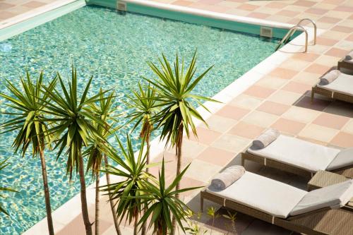 a swimming pool with two lounge chairs and palm trees at Doryssa Lithos Hotel in Pythagoreio