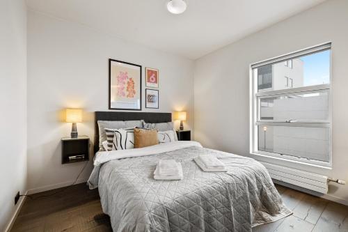 a white bedroom with a large bed and a window at Unbeatable Central Location - Reykjavíks Most Exclusive Luxury Apartments in Reykjavík