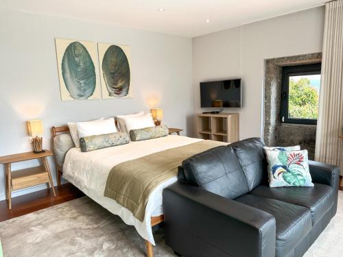 a bedroom with a bed and a leather couch at Villa Isobel in Vila Verde