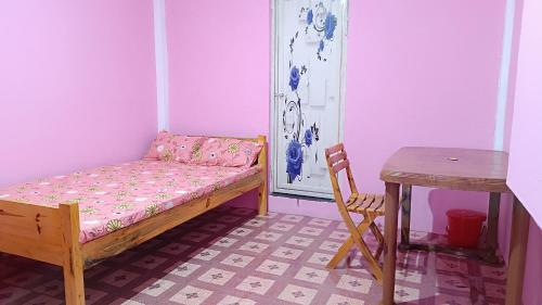 a small room with a bed and a table at PAMILYA HOMESTAY in Cherrapunji
