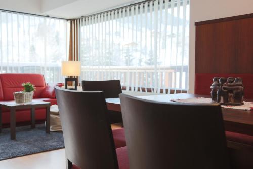 a living room with a table and chairs and a large window at WOHNEN by LIZZY in Wagrain