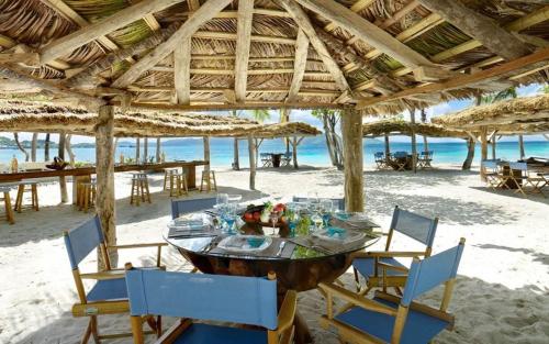 a table on the beach with chairs and umbrellas at Petit St. Vincent Resort in Petite Martinique