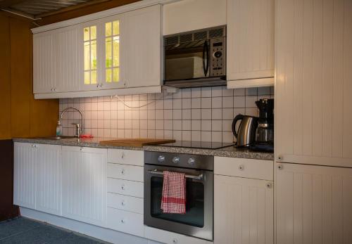 a kitchen with white cabinets and an oven at Bergmannsgata 3 in Røros