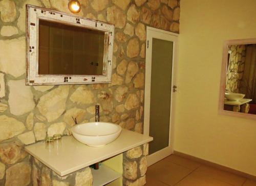a bathroom with a sink and a stone wall at Kleinzee Oceanfront Guesthouse in Gansbaai