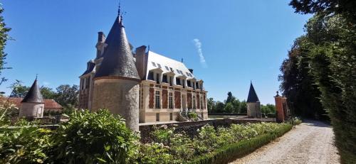 un antiguo edificio con torretas y un camino de tierra en Château de Bonaventure, en Aulnoy