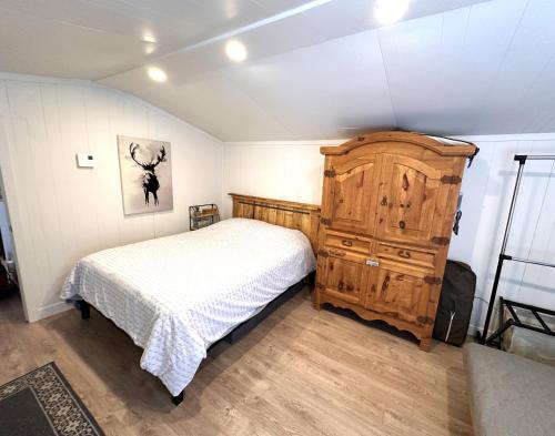 a bedroom with a bed and a wooden dresser at Petit chalet au bord de la rivière in Saint Mathieu Du Parc