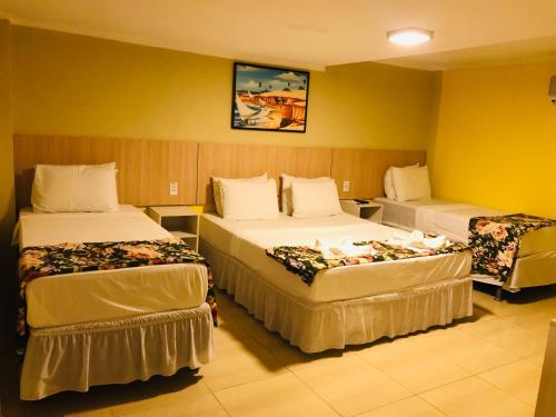 a hotel room with two beds in a room at Hotel Pousada Latitude in Canoa Quebrada