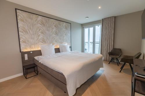 een slaapkamer met een groot bed, een bureau en een raam bij Residentie de Schelde - Apartments with hotel service and wellness in Cadzand-Bad