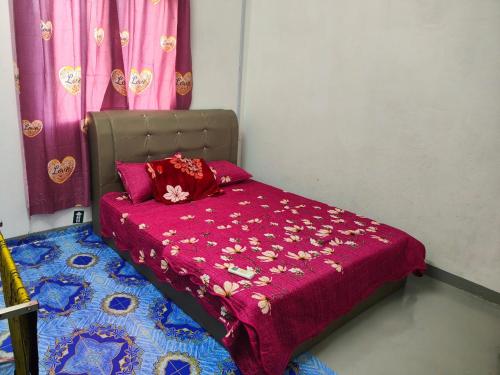 a small bed with a red blanket and pink curtains at My Soul Homestay in Kampong Ru Sepuloh