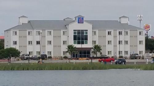 a large white building next to a body of water at Motel 6-Eagle Pass, TX - Lakeside in Eagle Pass