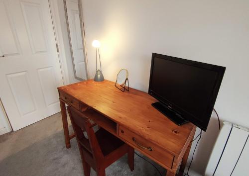 a television on a wooden desk with a lamp on it at Stunning One Bedroom Holiday Flat In Weymouth in Weymouth