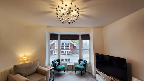 a living room with a television and a chandelier at Stunning One Bedroom Holiday Flat In Weymouth in Weymouth