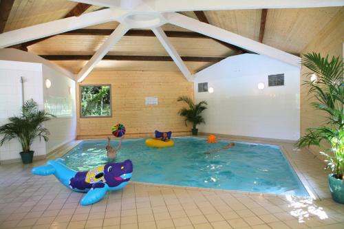 uma grande piscina interior com um tubarão insuflável numa sala em Olydea Oleron les Sables Vignier em Saint-Georges-dʼOléron