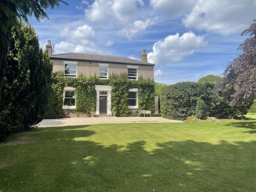 una casa grande con un césped verde delante de ella en Croxton House en Kirmington