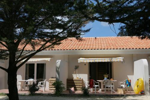 uma casa com cadeiras e mesas e um telhado em Olydea Oleron les Sables Vignier em Saint-Georges-dʼOléron
