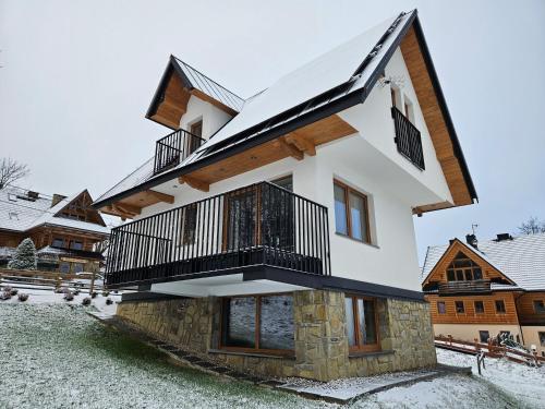 uma casa na neve com uma varanda em Galicówka na Górce Domki em Biały Dunajec