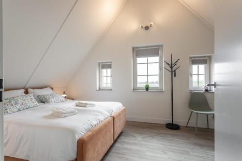 1 dormitorio con 1 cama con sábanas blancas y ventanas en Hello Zeeland - Vakantiewoning Knuitershoek 104, 