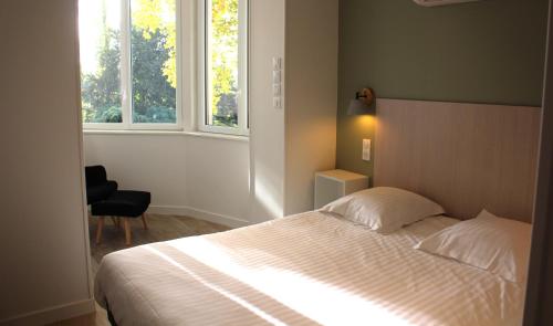 um quarto com uma cama, uma cadeira e 2 janelas em Villa Marronniers - Superbe appartement neuf, 4 personnes em Bourbon-Lancy