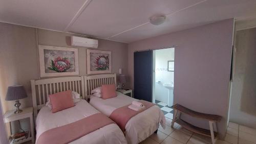 1 Schlafzimmer mit 2 Betten und rosa Kissen in der Unterkunft SuNel's Guest Rooms in Malmesbury