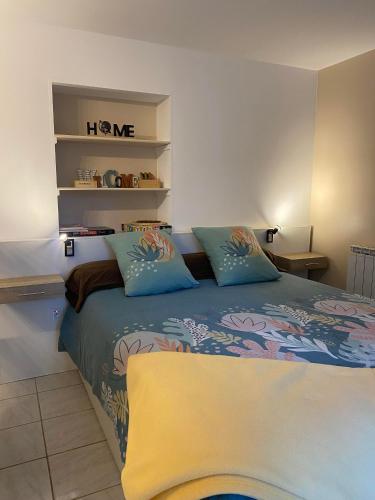 une chambre avec un lit avec des oreillers bleus dans l'établissement Le Refuge, à Montmeyan