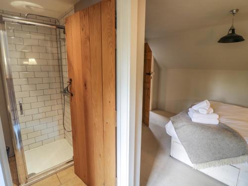 ein Bad mit Dusche und ein Bett mit Handtüchern in der Unterkunft The Cottage in Chipping Campden