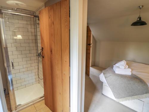 a bathroom with a shower and a bed with towels at The Cottage in Chipping Campden