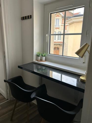 einen Schreibtisch in einem Zimmer mit 2 Stühlen und einem Fenster in der Unterkunft Appart' Studio cooconing - Champs Elysées - JO 2024 in Maisons-Laffitte