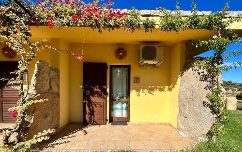 a yellow house with flowers on the side of it at Hotel I Menhirs in Annunziata