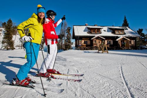 dos personas esquiando en la nieve frente a una cabaña en Galsterbergalm Jagdhütte, en Auberg