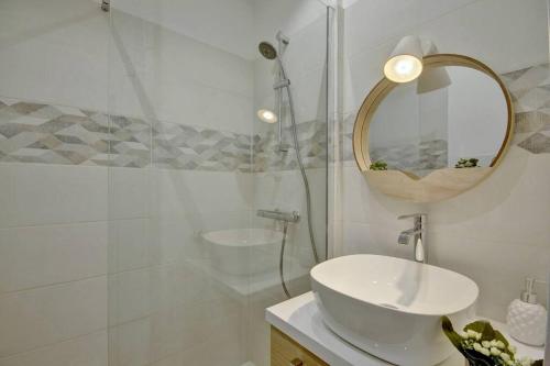 une salle de bain blanche avec un lavabo et un miroir dans l'établissement Le Chandelier - Magnifique T2 Quartier St Pierre, à Bordeaux