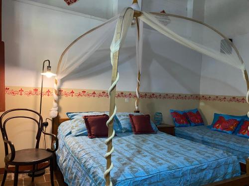 a bedroom with a canopy bed and a chair at CASA SINNING-año1637 in Mompos