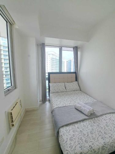 um quarto com uma cama e duas janelas em Love Grande - 2BR AZURE URBAN em Manila