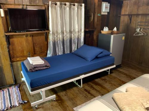 una camera con letto con lenzuola blu e TV di เมี่ยงไม้ รีสอร์ท a Ban Khlong Khen