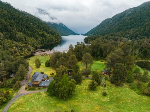 an aerial view of a house next to a lake at El Pangue Lodge in Puerto Puyuhuapi