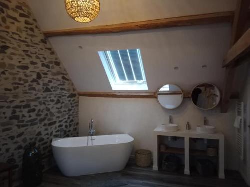 a bathroom with a tub and two sinks and a window at Le Buron du Bessou in Saint-Urcize