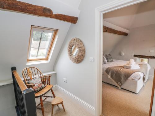 a bedroom with a bed and a chair and a window at The Old Brewhouse in Chipping Campden