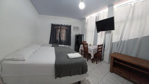 1 dormitorio con 1 cama, 1 silla y TV en Piratininga Guesthouse Casa de Hóspedes en Niterói