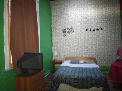 1 dormitorio pequeño con 1 cama y TV en Hostal del gato, en Valparaíso