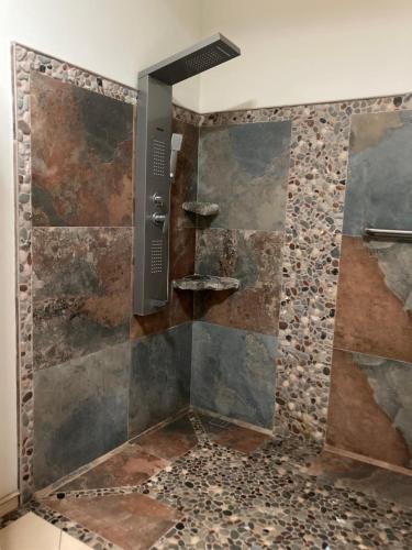 La salle de bains est pourvue d'une douche et d'un mur en pierre. dans l'établissement Garza Tigre Apartamentos, à Cóbano