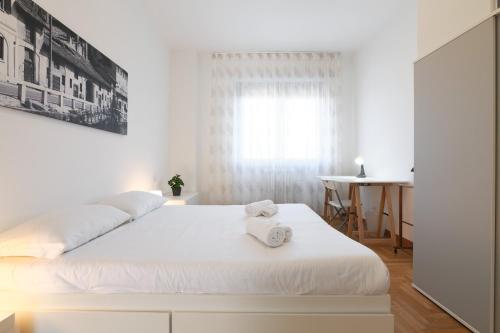 a white bedroom with a bed with two towels on it at PrimoPiano - Novara in Milan
